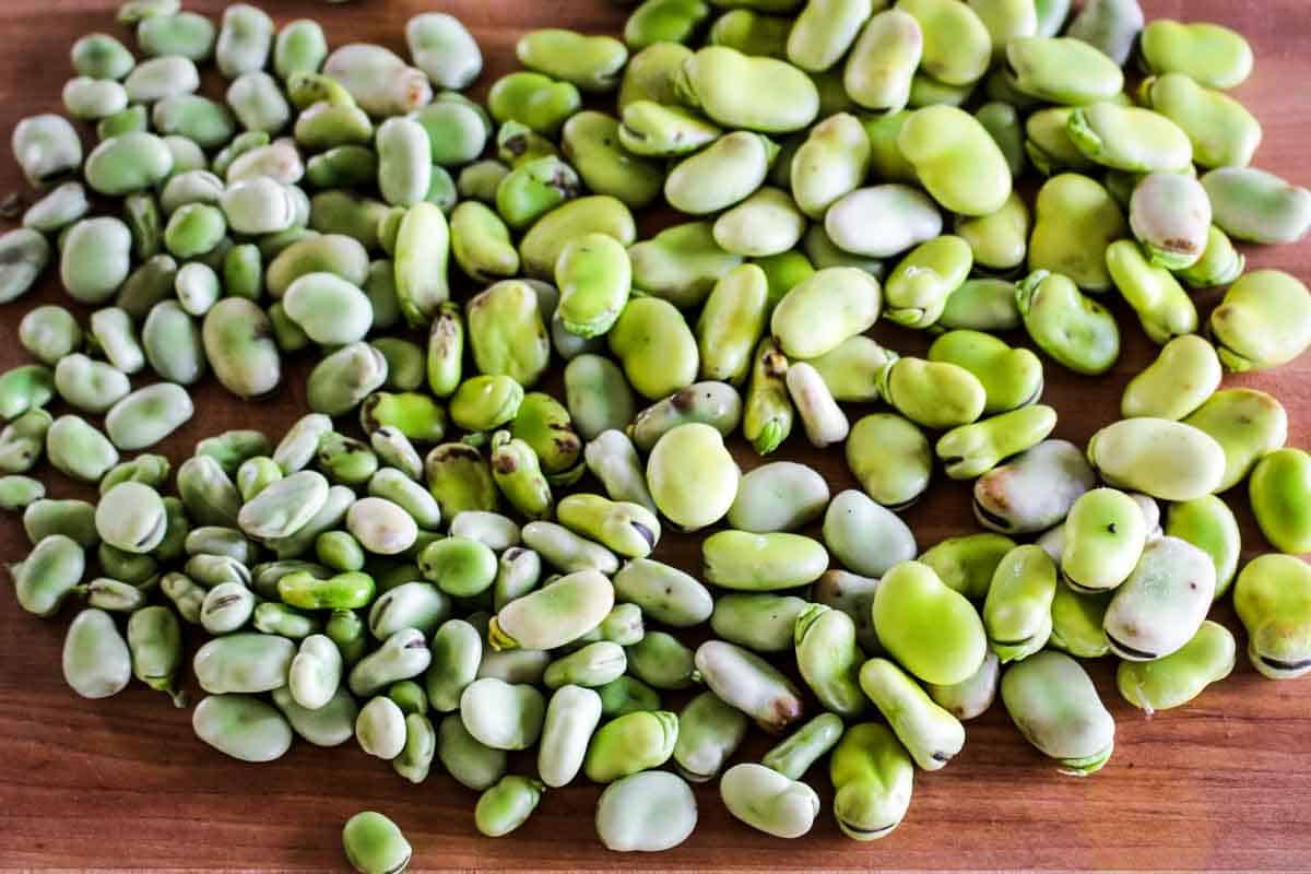 Shelled fava beans on a wooden board.