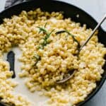 A spoon scooping homemade creamed corn from a pan.