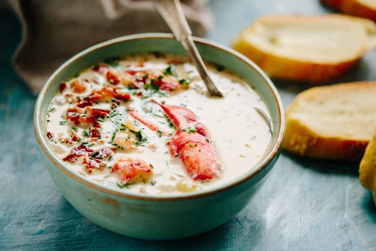 A steaming hot bowl of lobster chowder with corn.