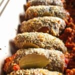 Breaded beef roll ups baked in a pan with bay leaves tucked in between each.