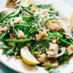 A platter of Italian tuna and green bean salad with lemon wedges.