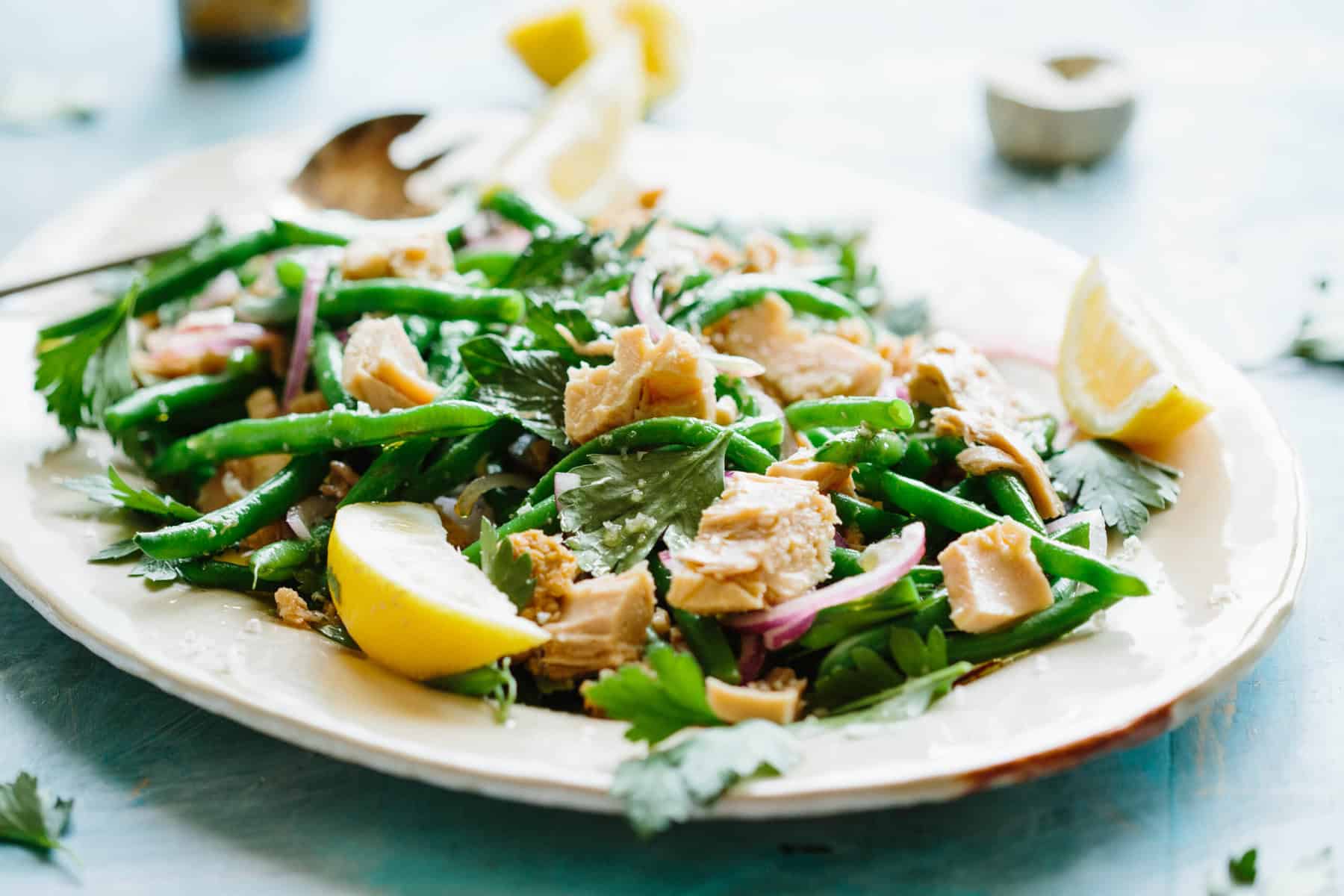 A serving plate of green beans and tuna salad with herbs.