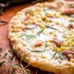 A white pizza with prosciutto, corn and tarragon.