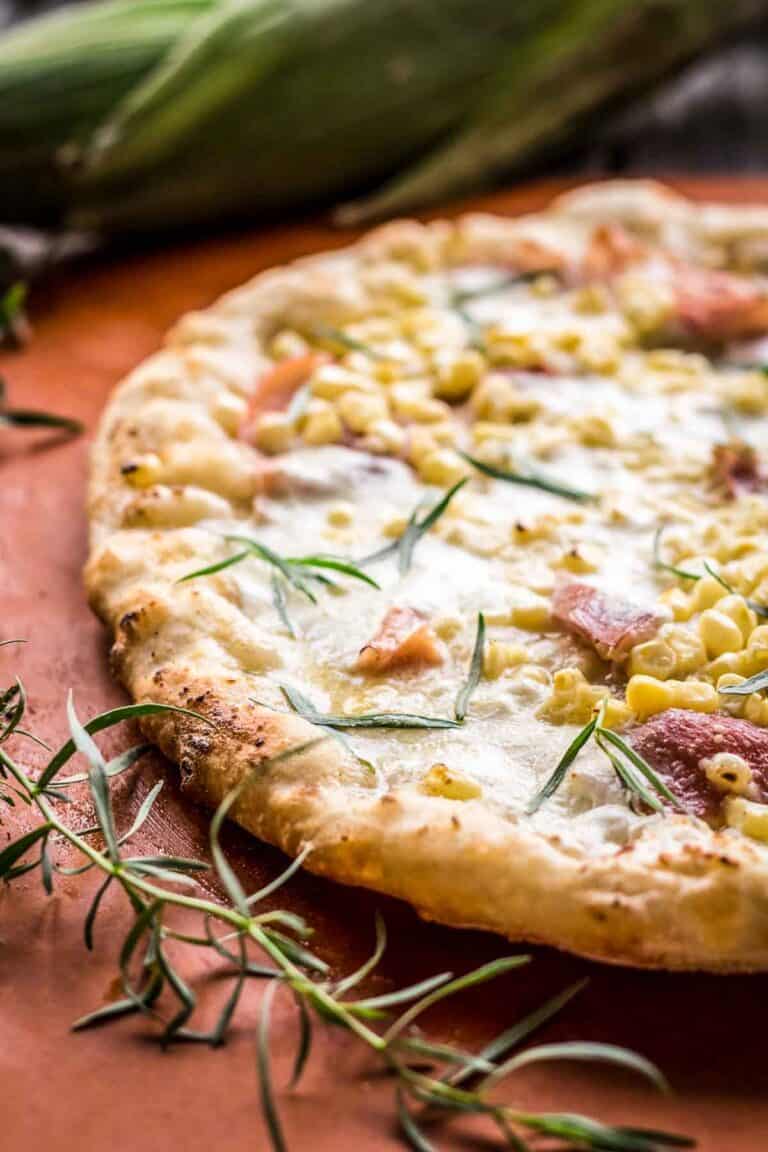 A white pizza with prosciutto, corn and tarragon.