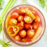 Carrot tops and sliced ginger in a jar in brine.