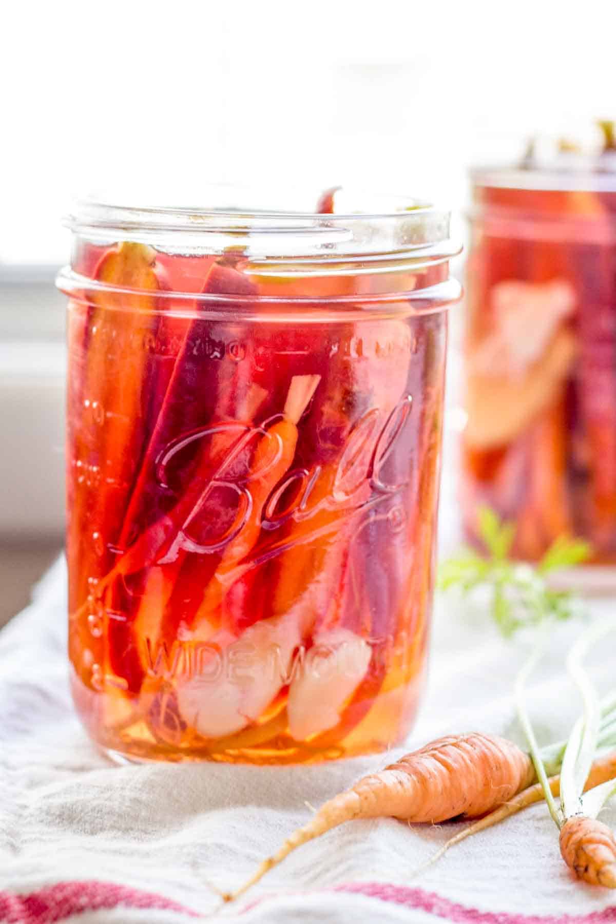 A jar of bright orange pickled carrots in brine.