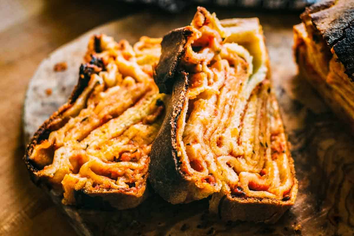 Slices of Scaccia ragusana with layers of tomato sauce and cheese.