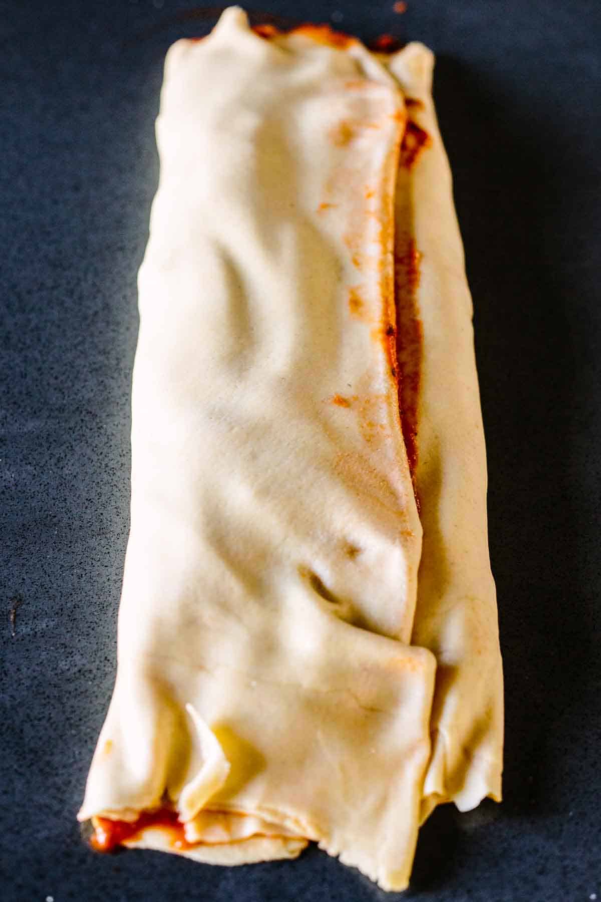 Scaccia ragusana dough being rolled up with its filling.
