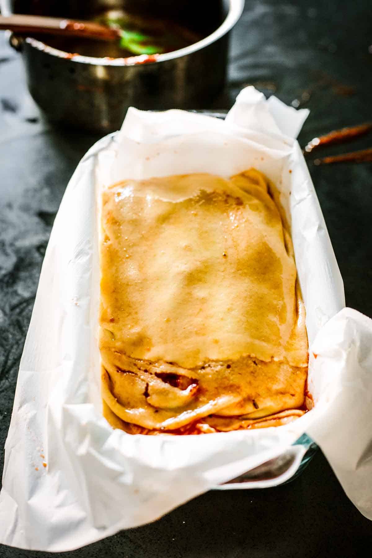 Raw scaccia ragusana in a bread baking dish ready for the oven.