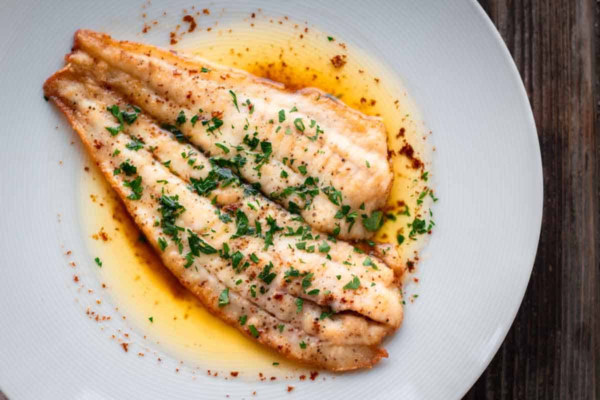 A fillet of flounder meunière on a white plate.