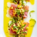 Raw tuna crudo with fresh basil, lemon, nuts and vibrant yellow olives oil.