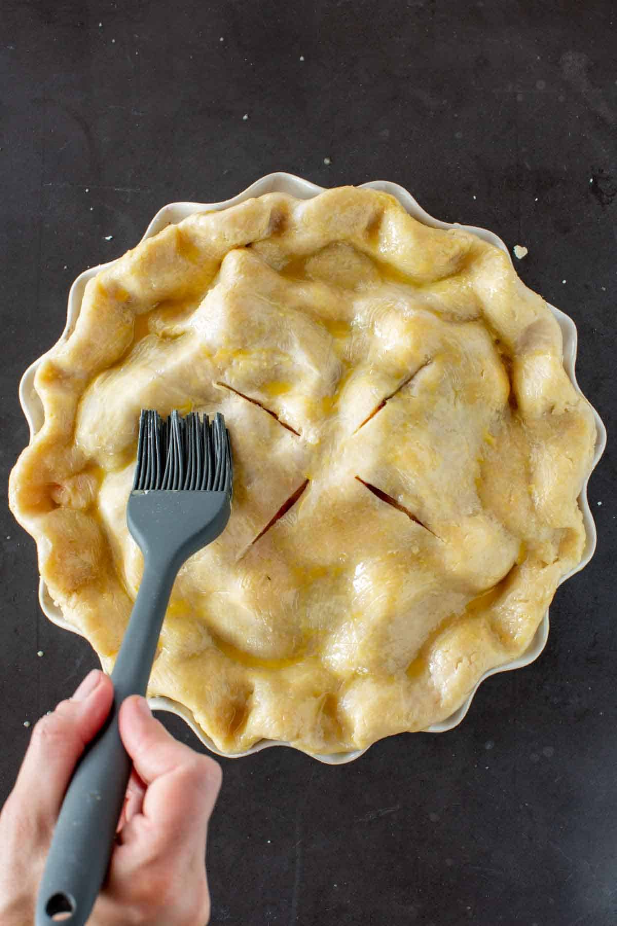 Brushing egg wash on a pie.