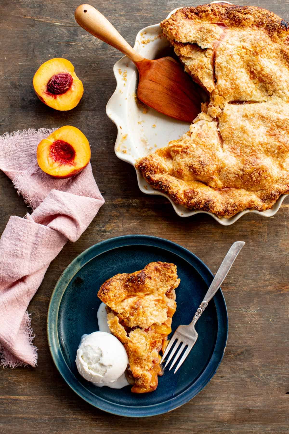A whole peach pie with a few pieces removed and a plate with a slice of pie and ice cream.