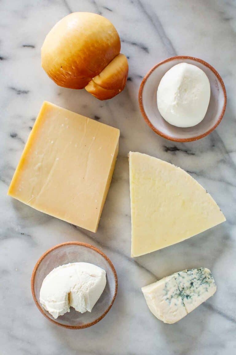 An assortment of hard and soft Italian cheeses on a marble board.