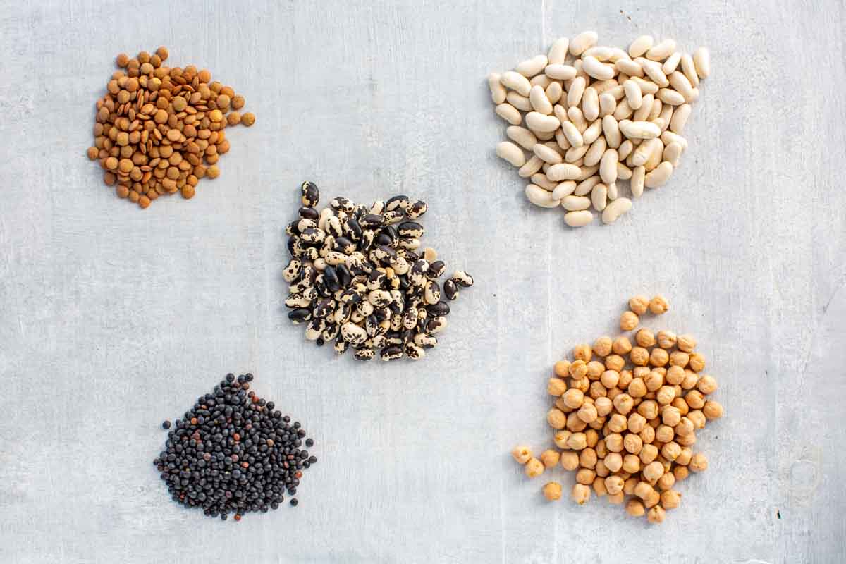 Piles of assorted dried legumes on a board.