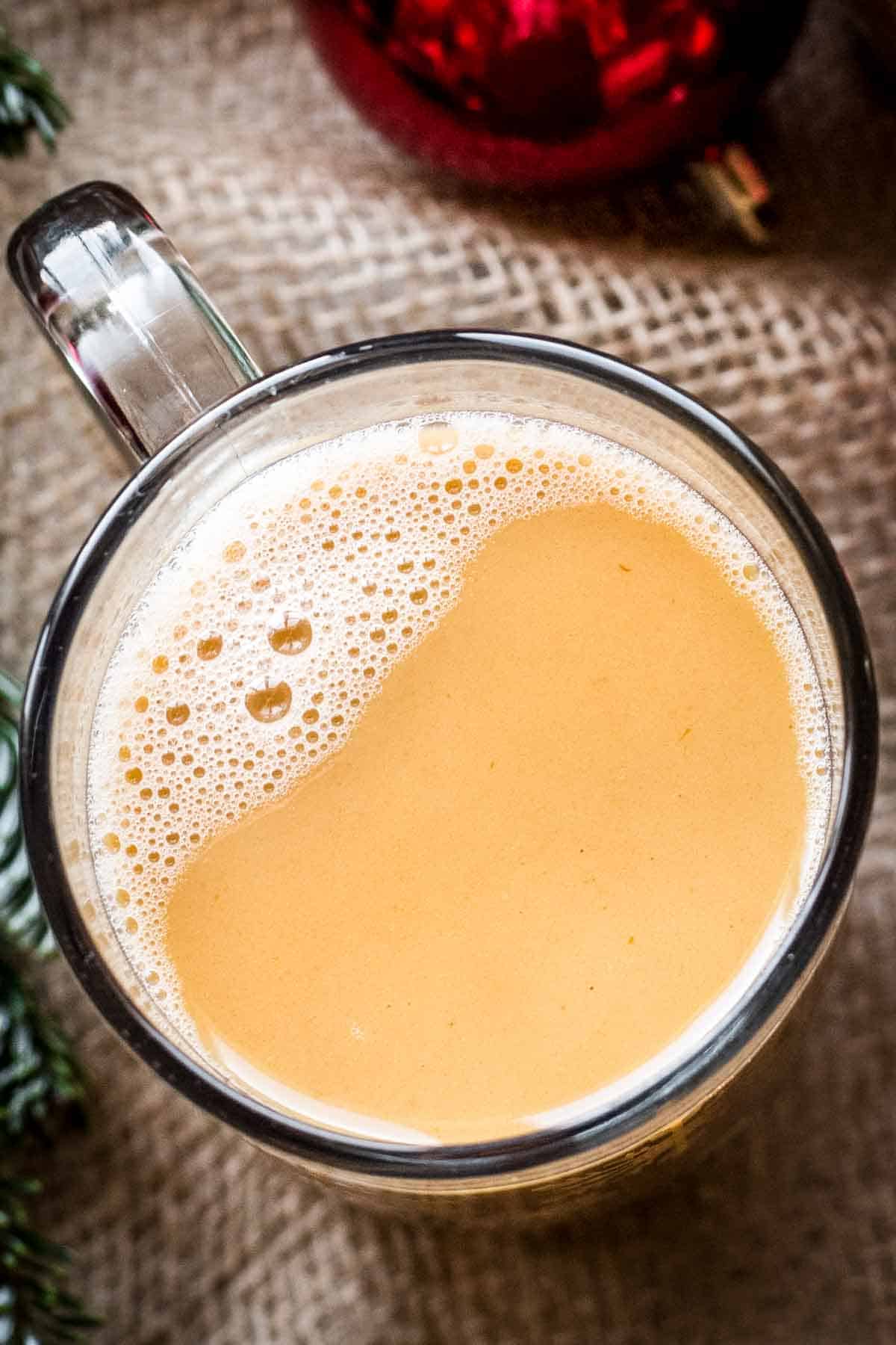 Overhead shot of a mug with hot buttered rum with frothy bubbles on top.