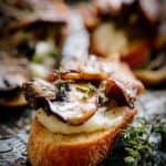 Close up of mushroom and cheese on crostini on a serving platter.