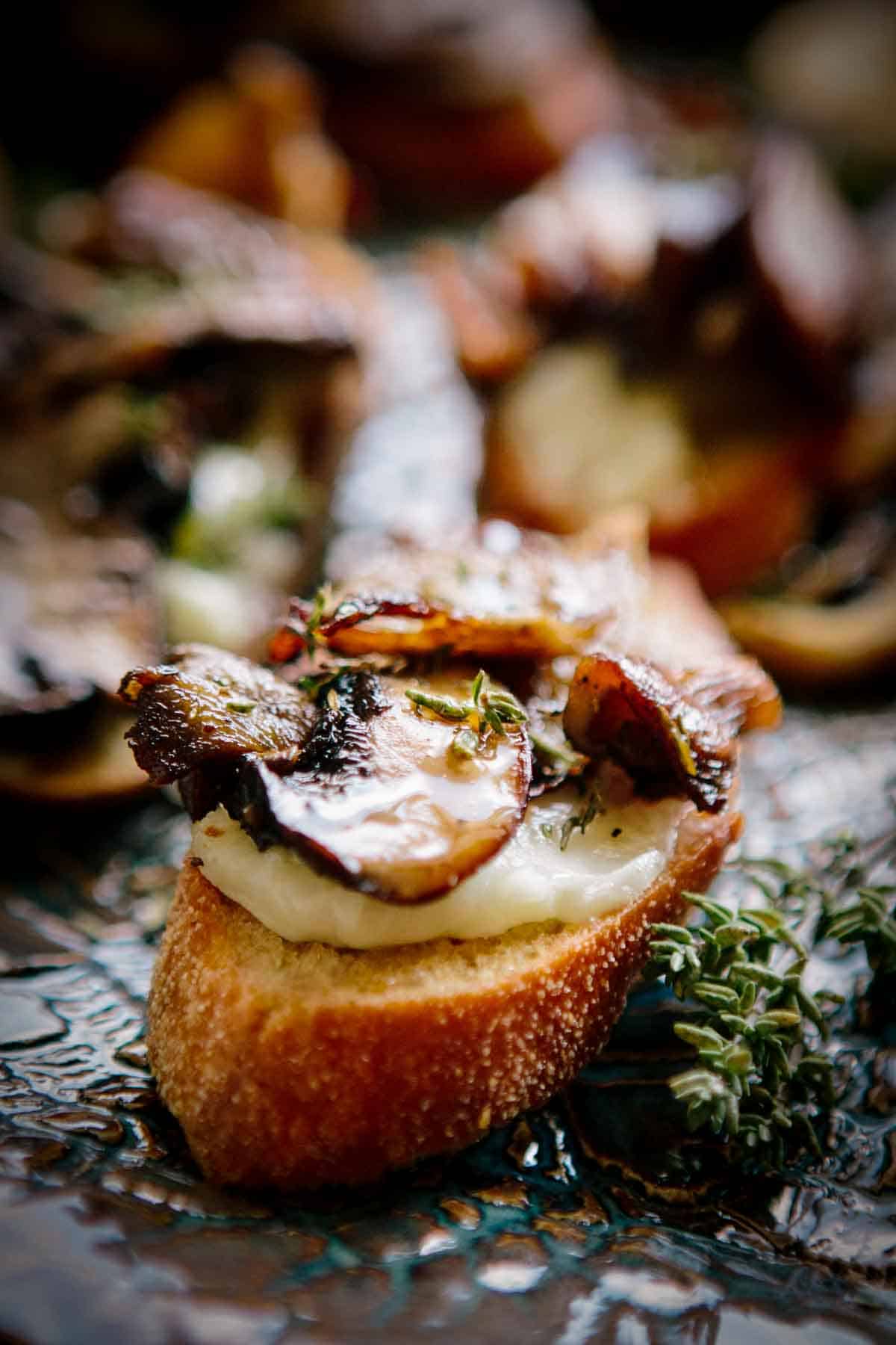 Close up of mushroom and cheese on crostini on a serving platter.