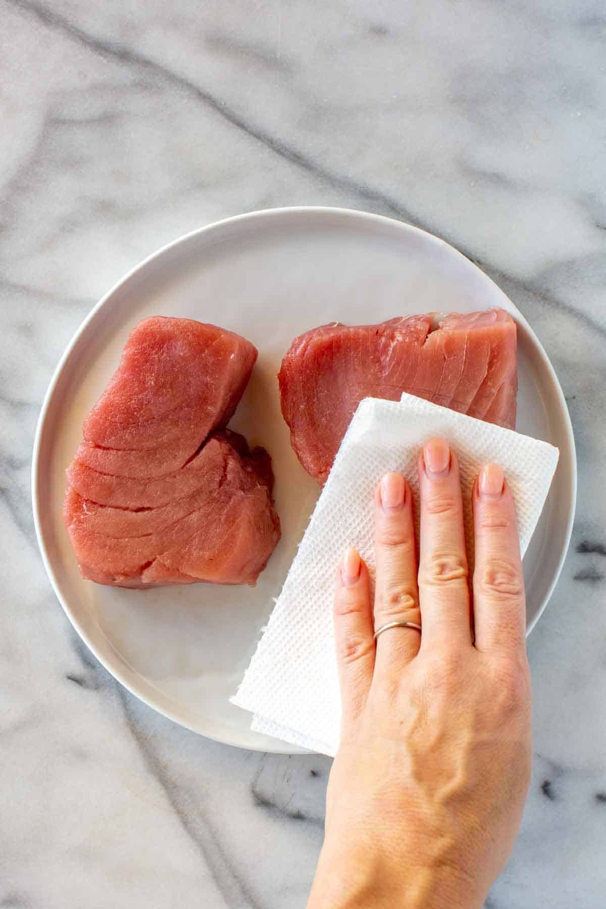 Patting tuna steaks dry.