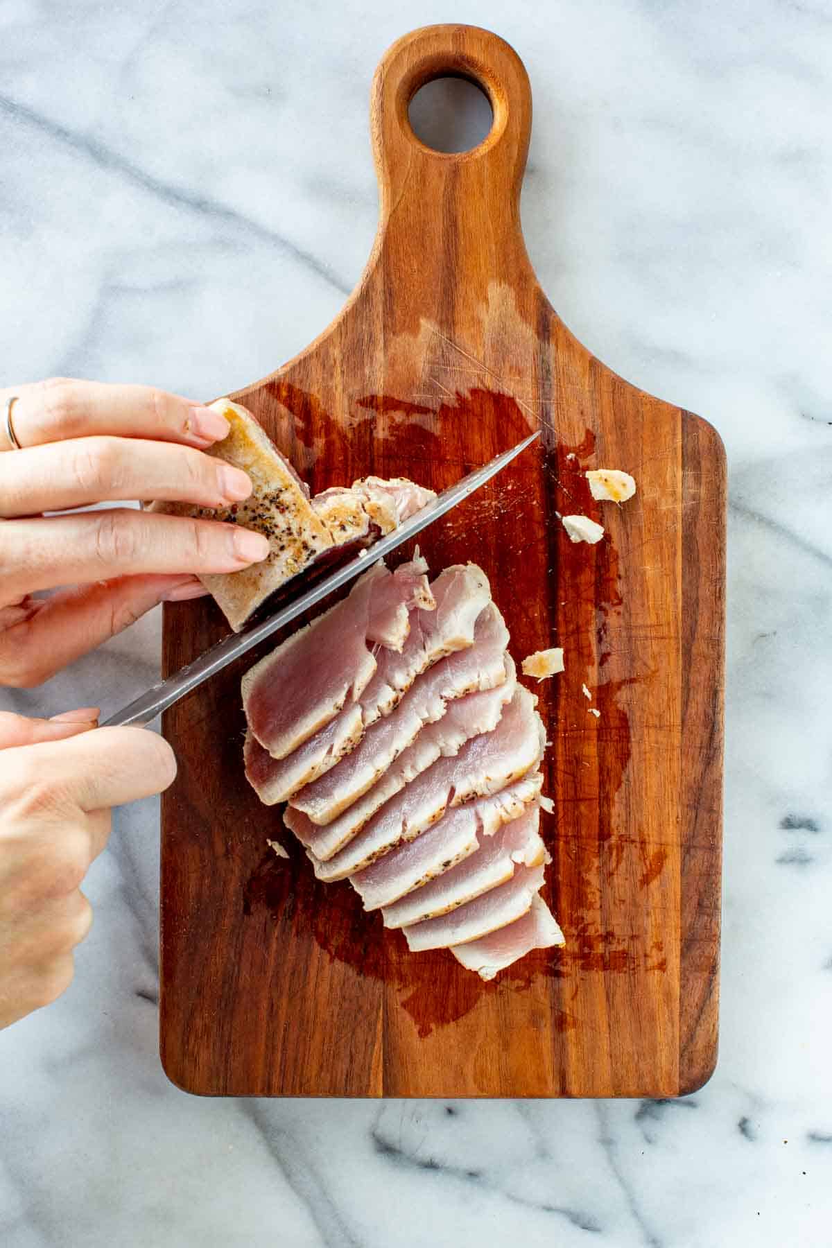 Thinly slicing a seared tuna steak.