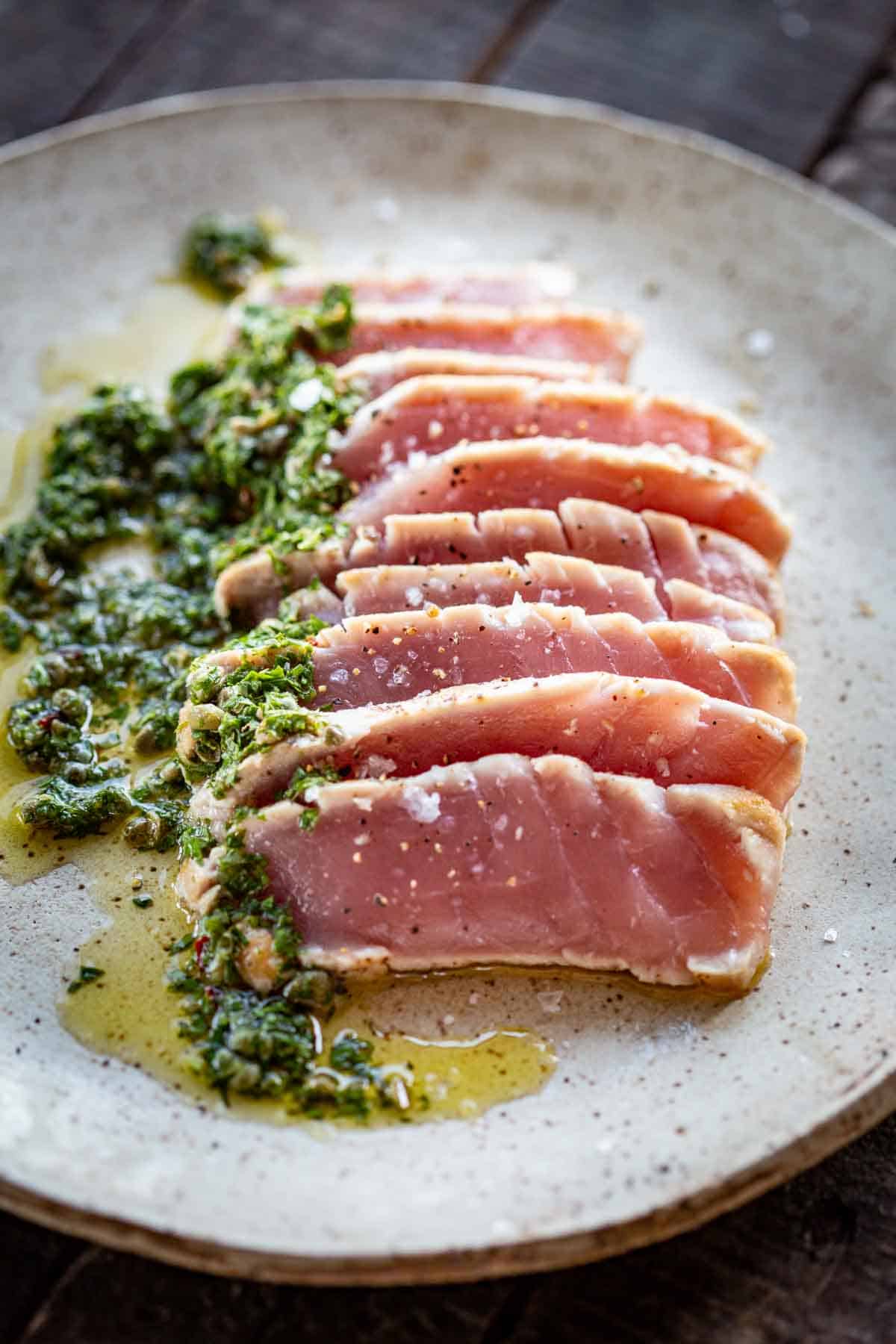 Close up of rare seared tuna with an olive oil herb sauce.