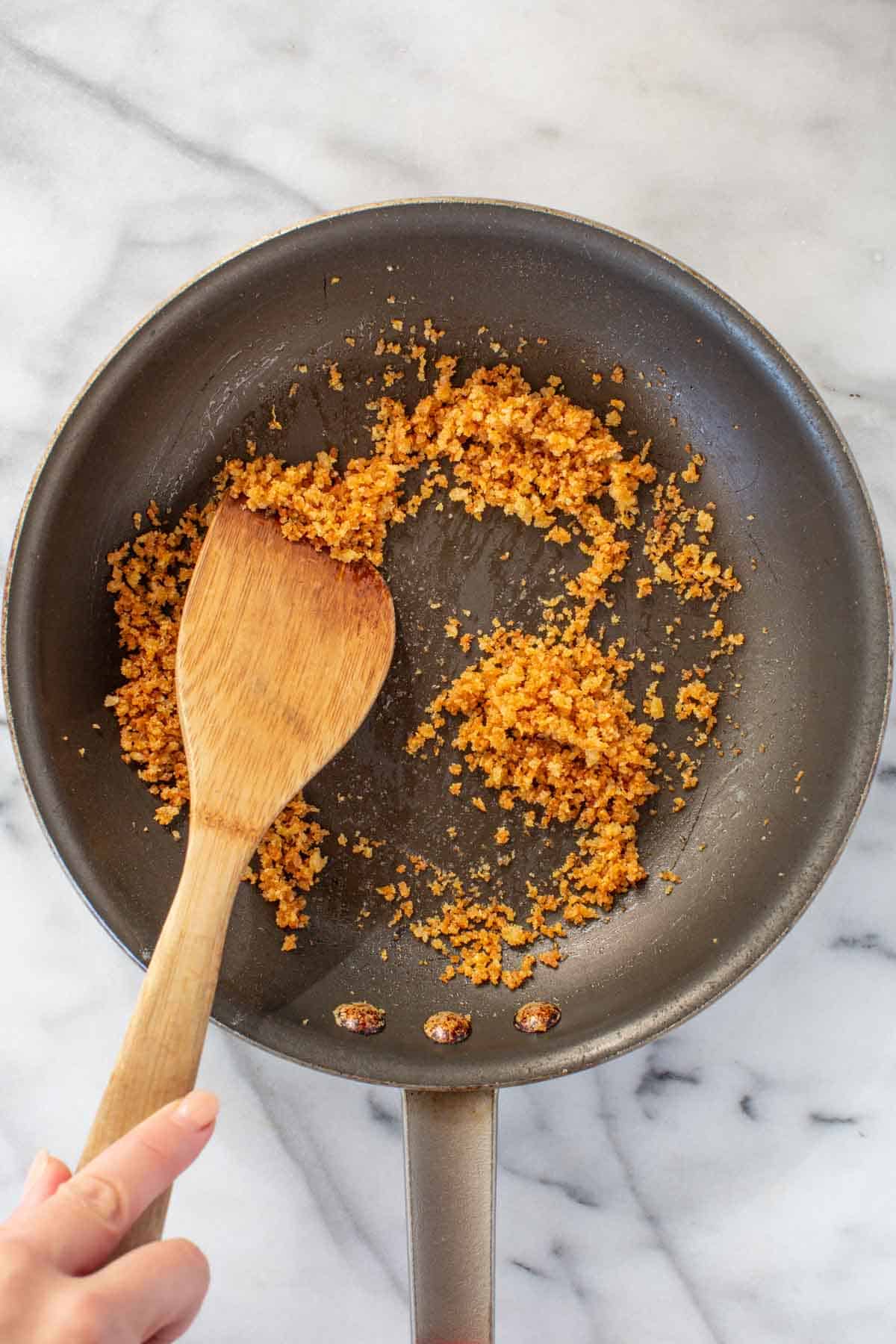 Stirring breadcrumbs in a pan.