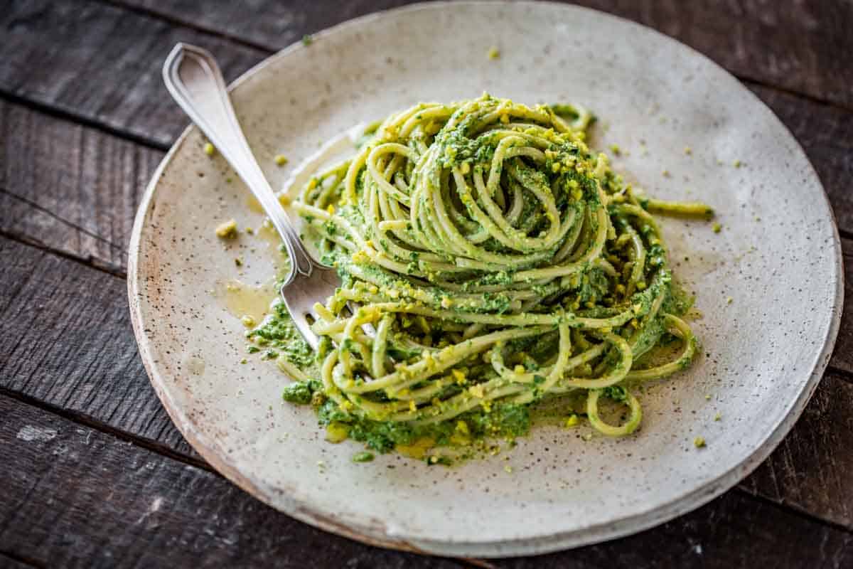 A ceramic plate with Sicilian pesto pasta and a fork.