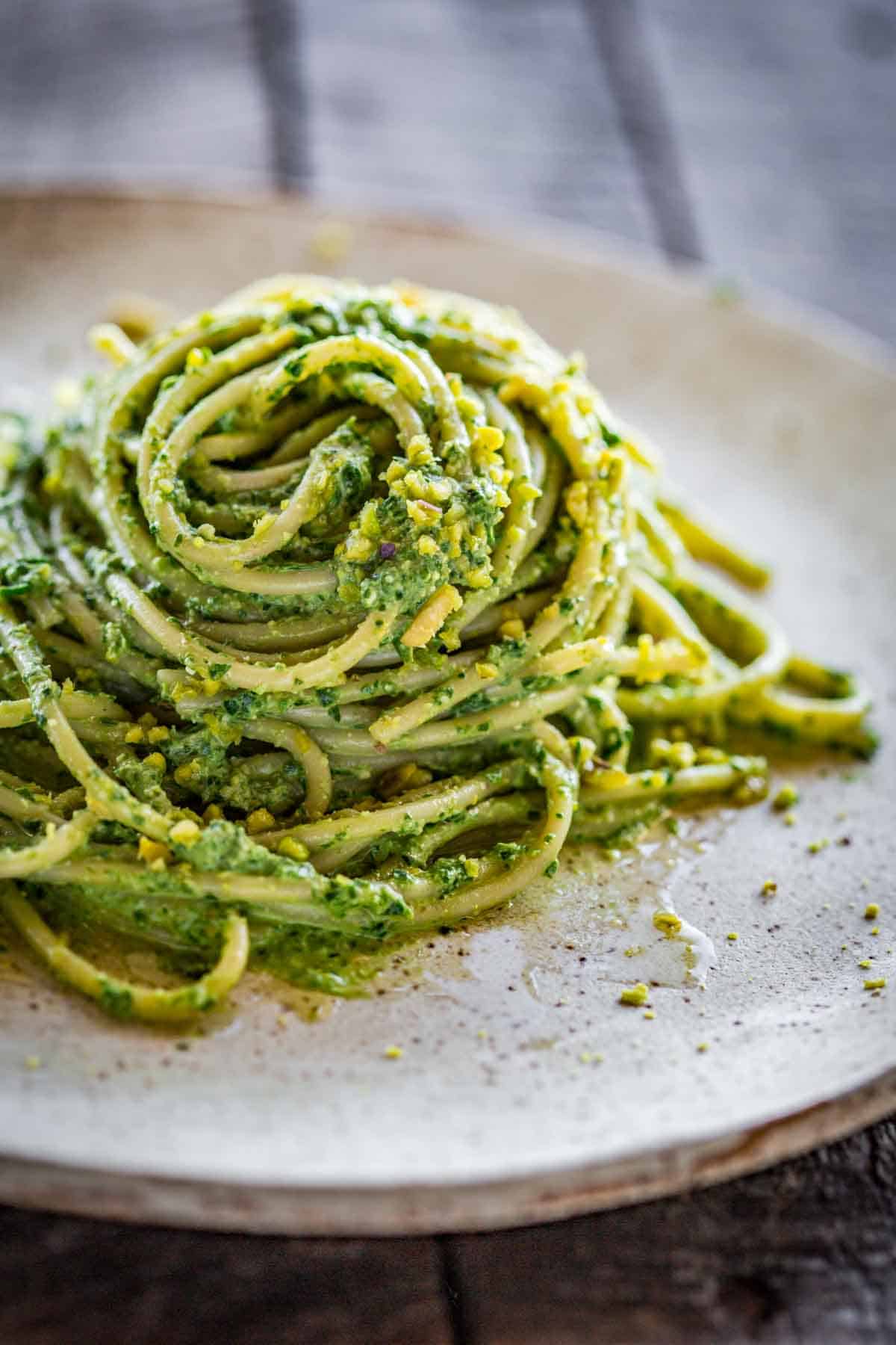 A mound of spaghetti tossed with vibrant green pesto.