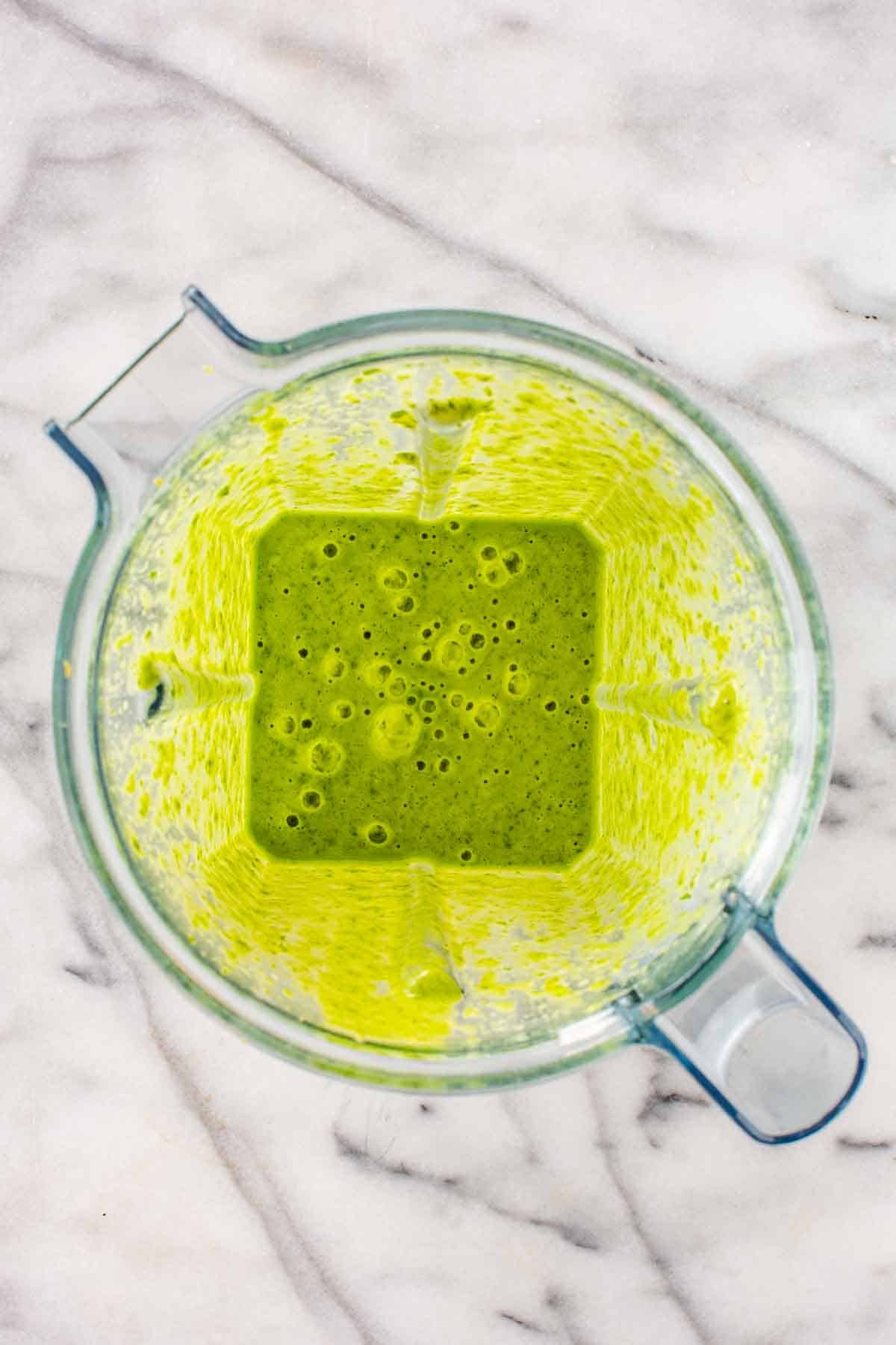 A blender with freshly blended green sauce.