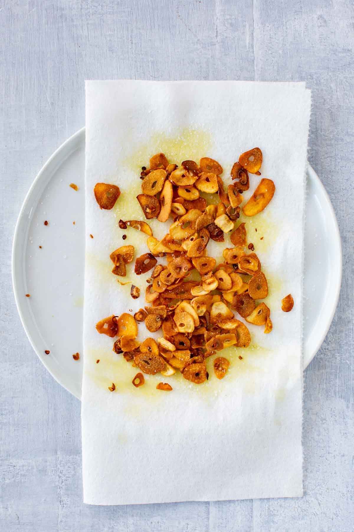 Crispy fried garlic chips draining on a paper towel.