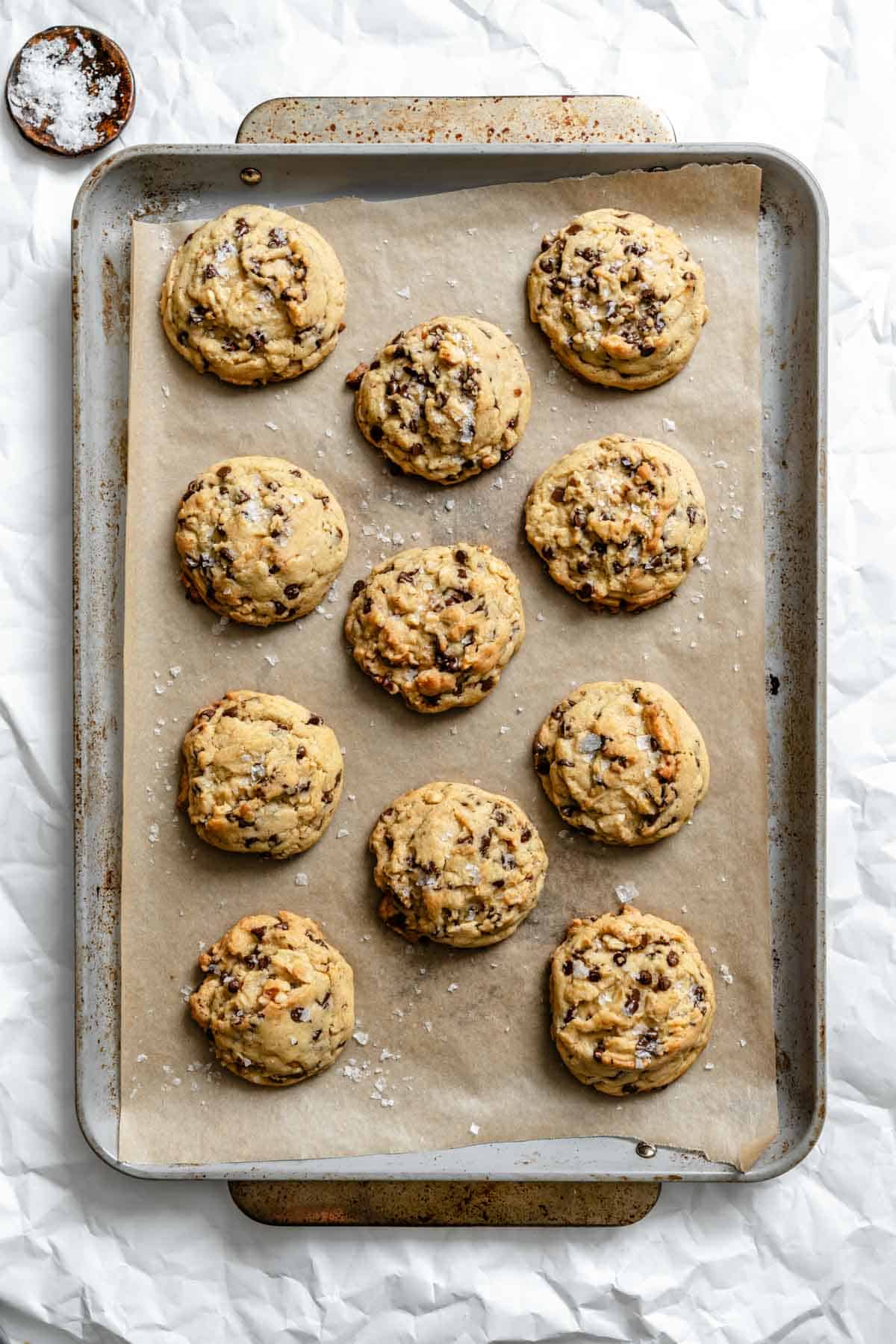 Freshly baked chocolate chip cookies on a baking sheet, showing golden edges and melted chocolate chips.
