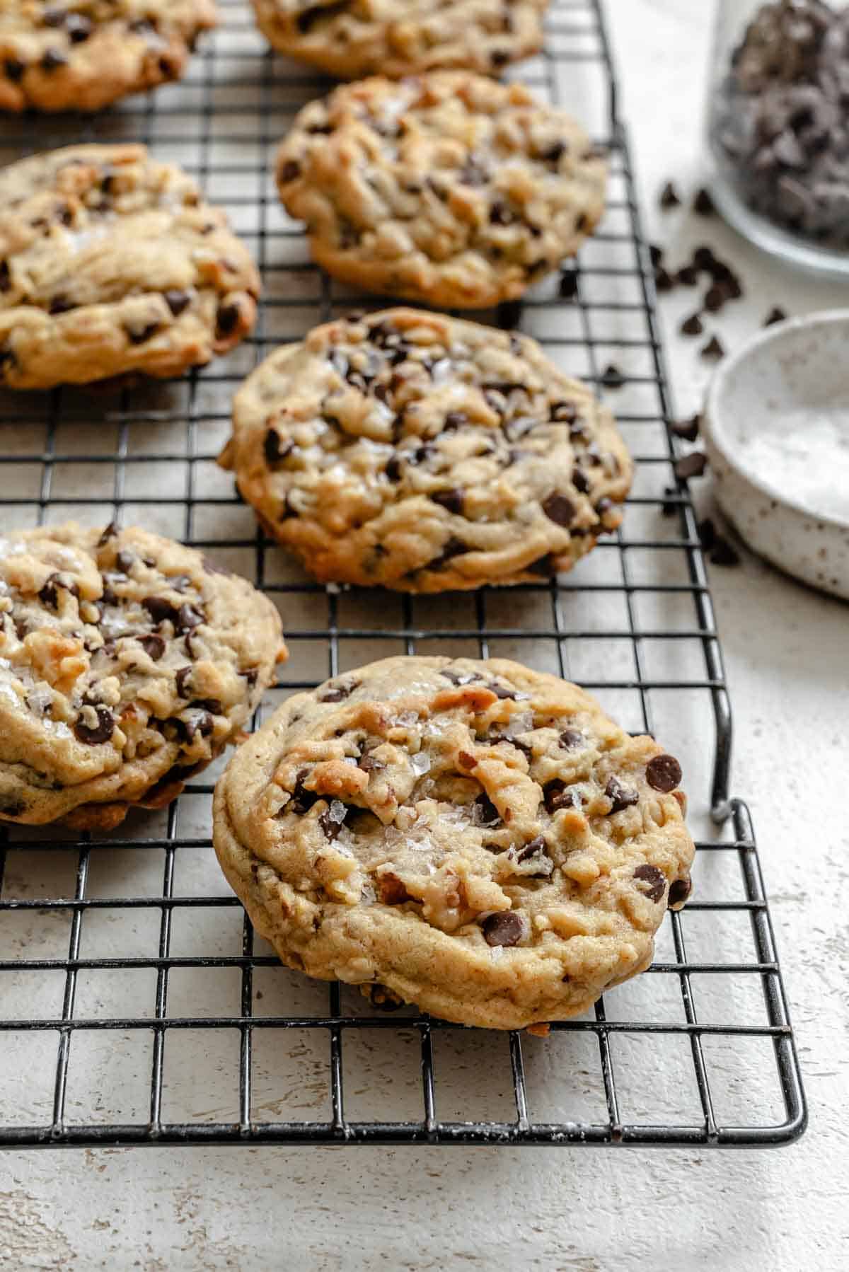 Multiple chocolate chip cookies arranged on a cooling rack, showing their texture and chocolate chunks.