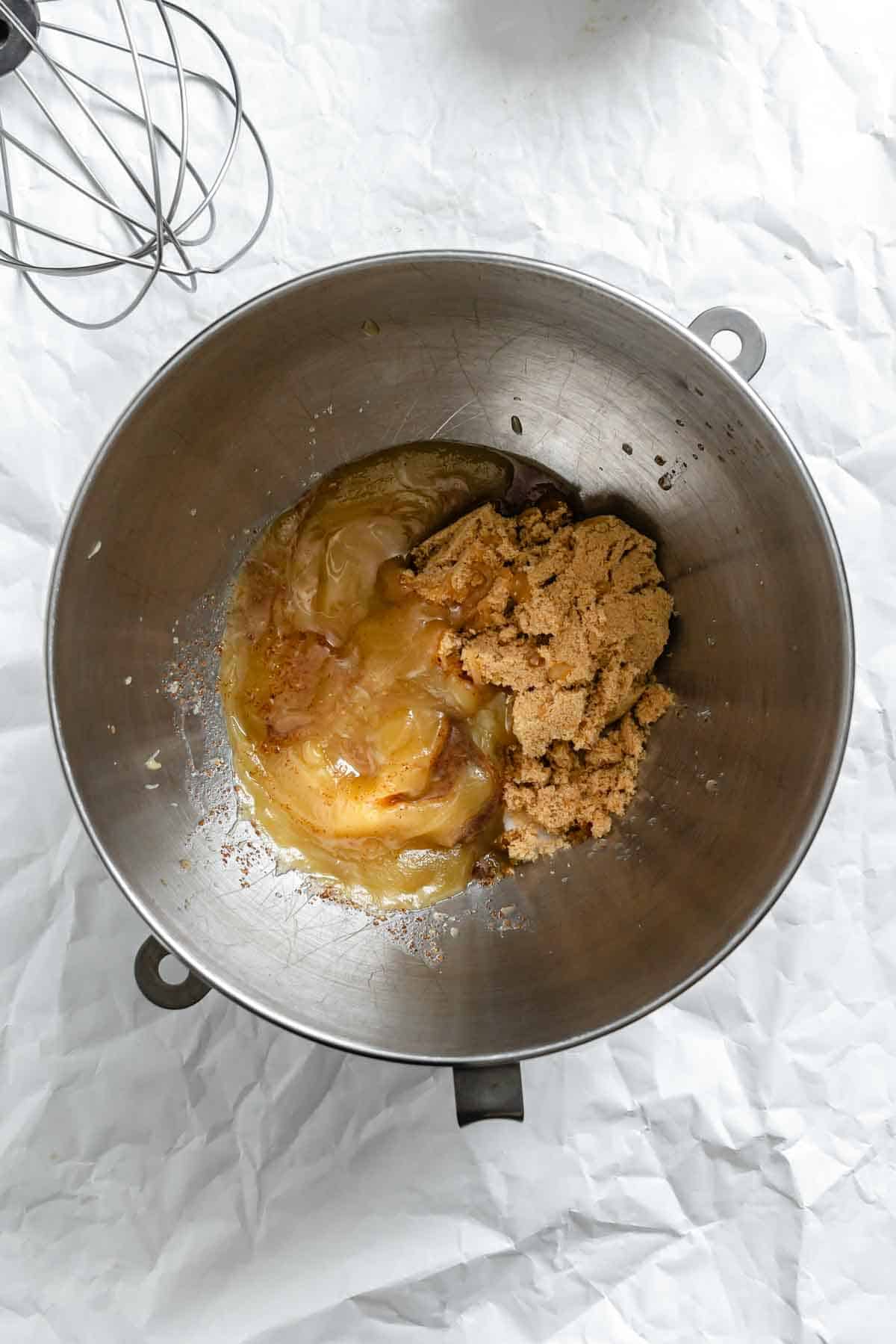 Mixing bowl containing brown butter and brown sugar being combined.