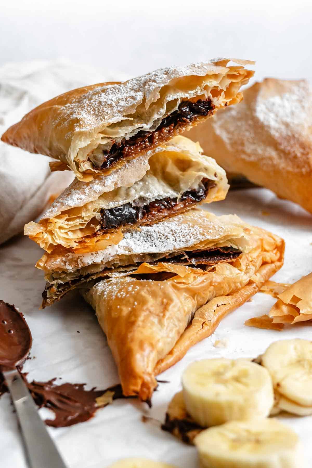 Close-up of broken phyllo triangles showcasing flaky layers and chocolate filling.