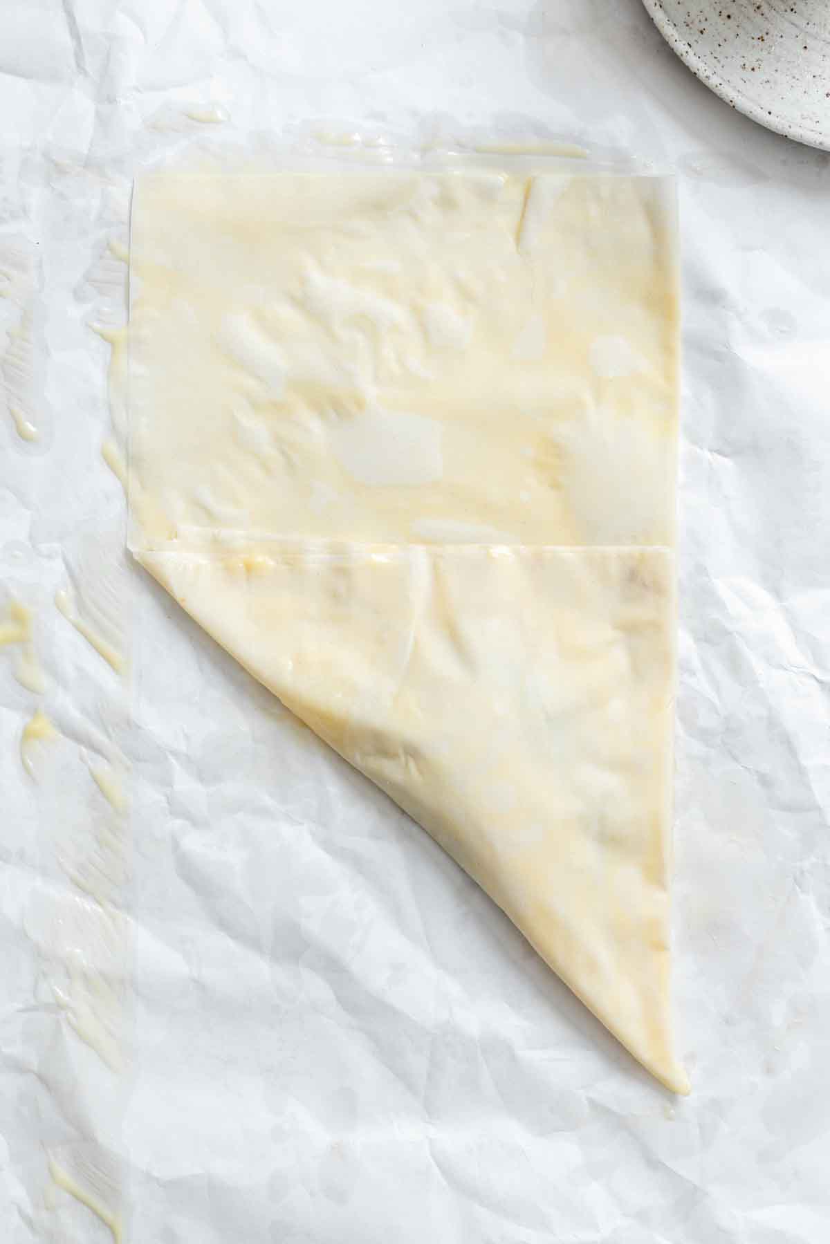 Triangular folded phyllo dough beside a plate with Nutella and banana slices.