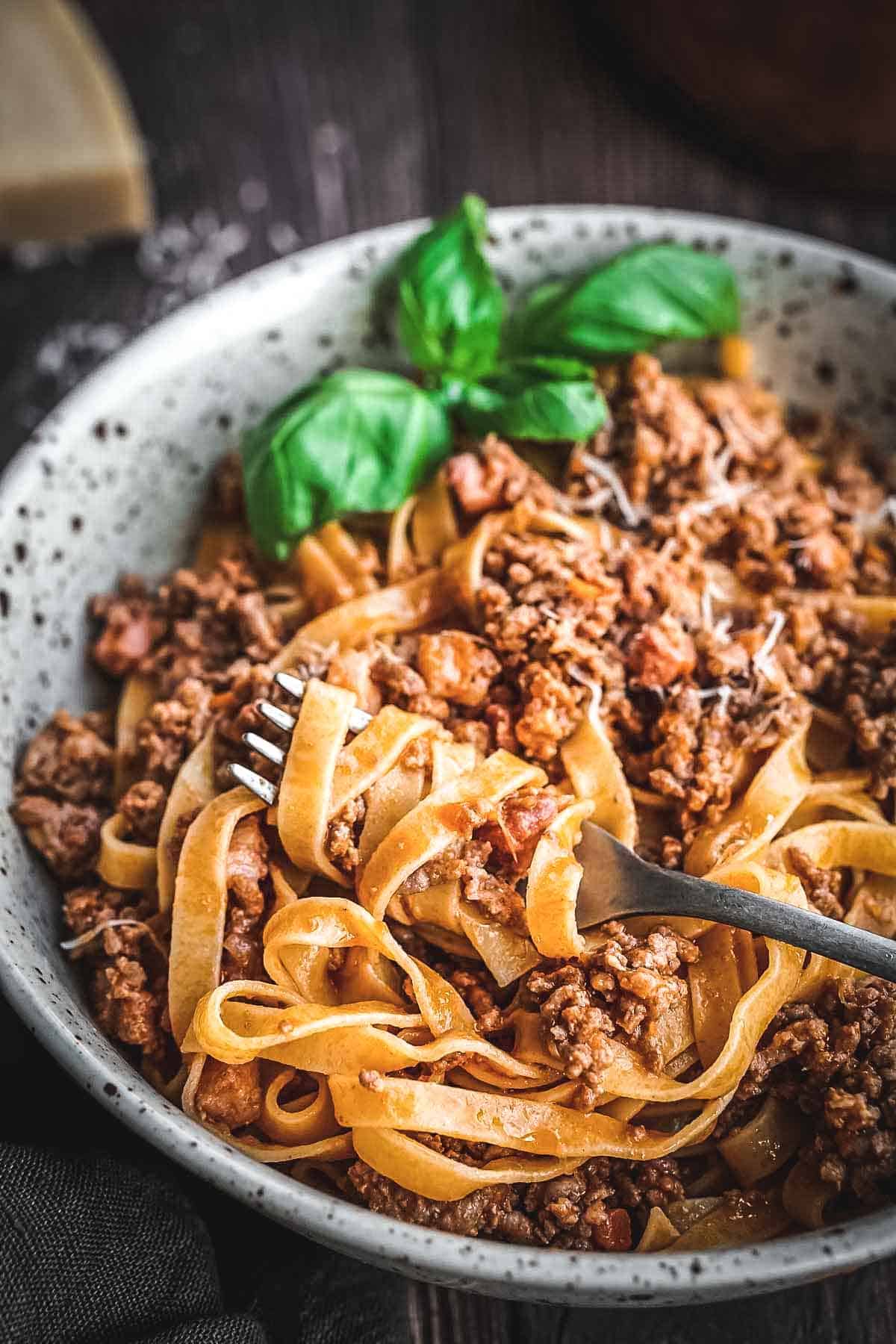 A fork twirling pasta with meat sauce.