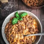 A bowl of pasta with ragu alla Bolognese with a fork.