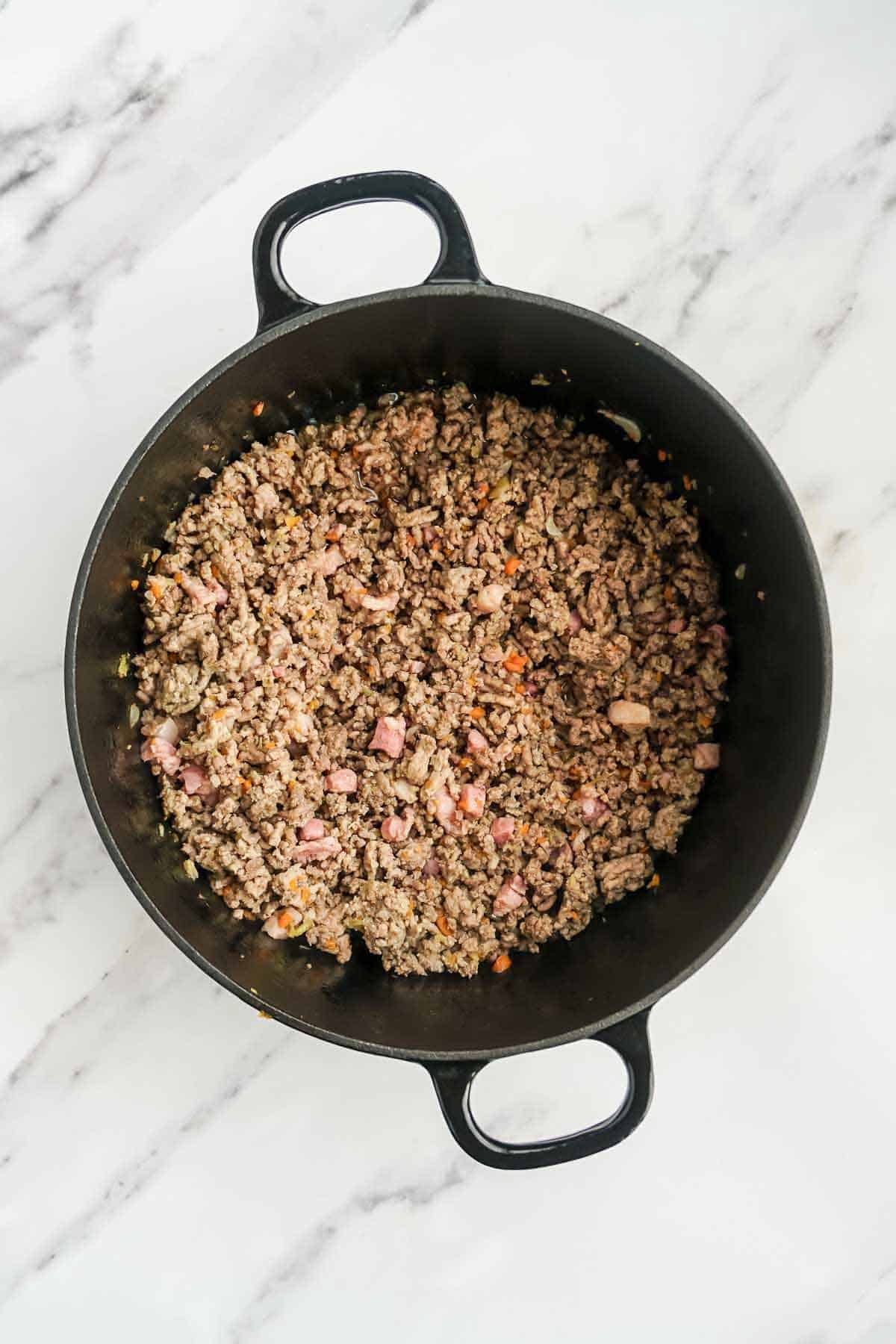Browned meat and vegetables in a pan.