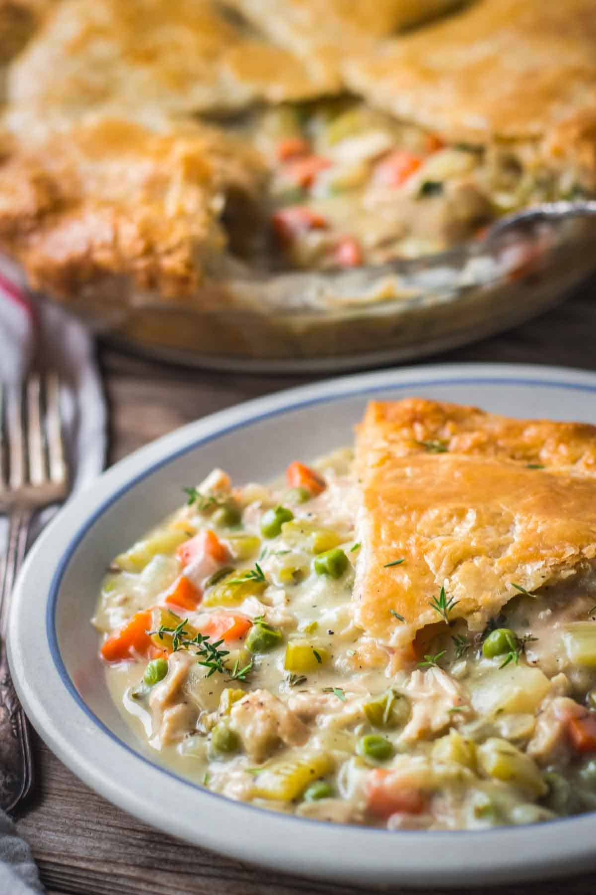 A slice of pot pie crust served on top of a plate, with the filling spread around it.