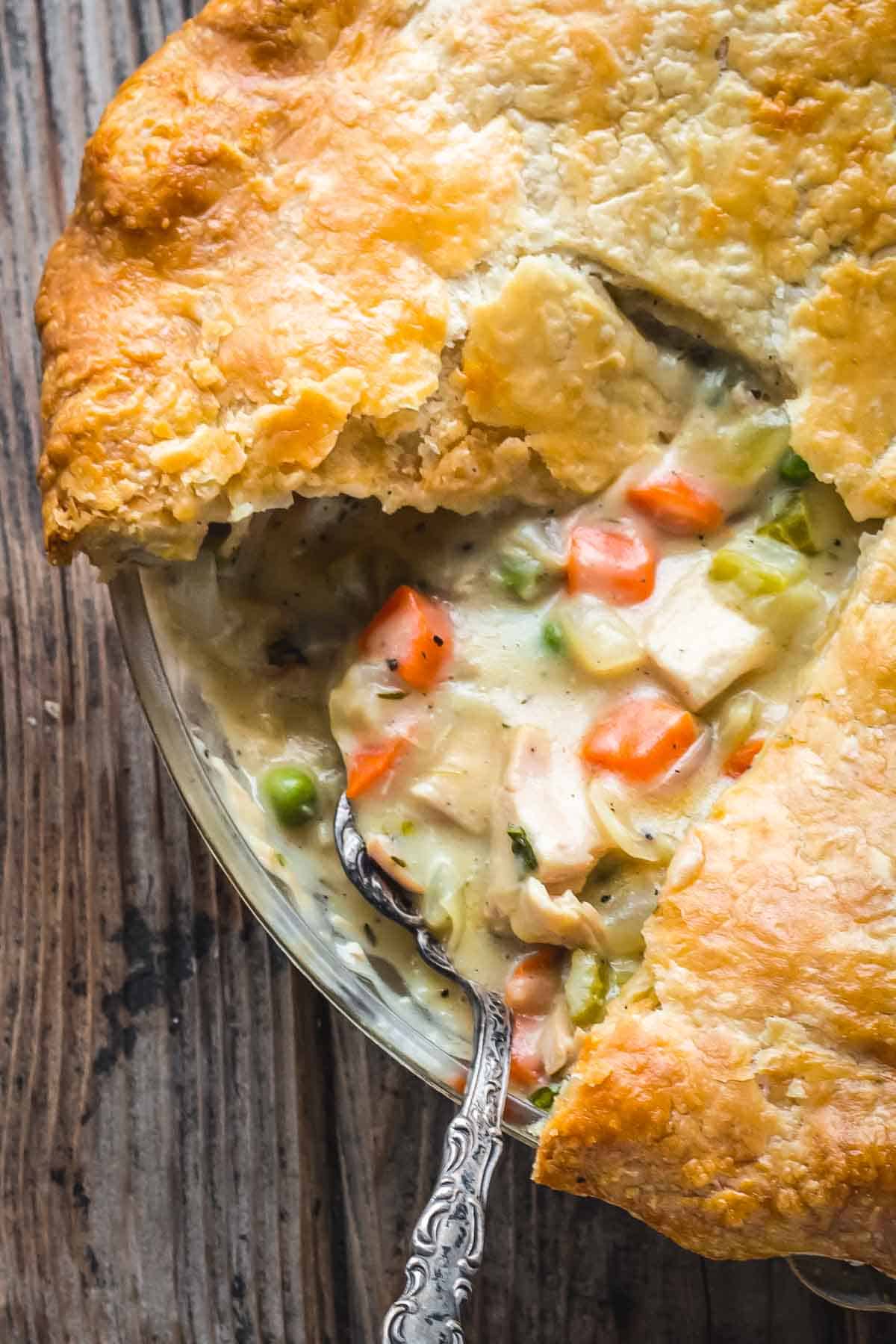 Close up overhead shot of the chicken pot pie after a slice has been removed, with a spoon scooping out the filling.