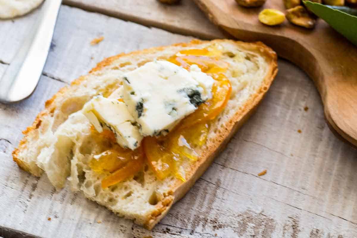 Meyer lemon marmalade served on top of a loaf of sourdough bread with a chunk of herbed butter.