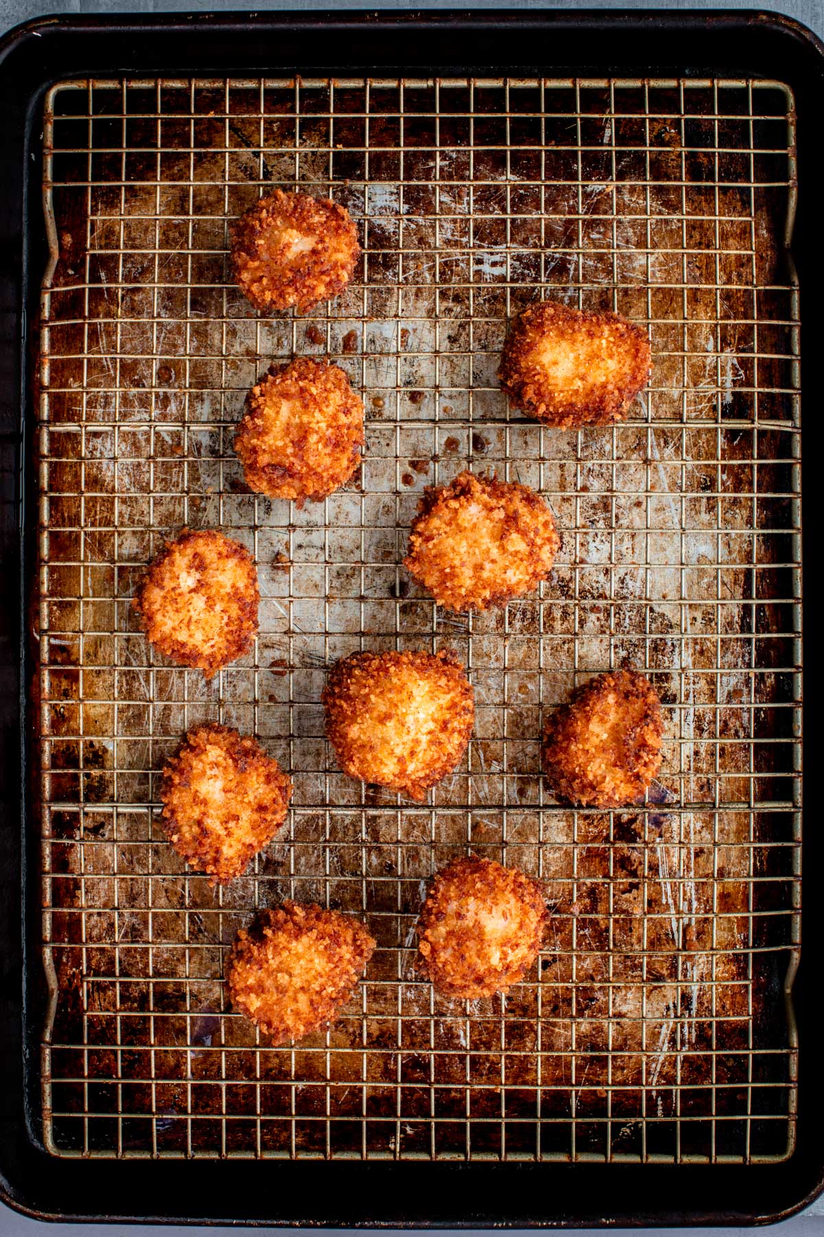 Overhead view of fried scallops resting on a wire rack set over a sheet pan.