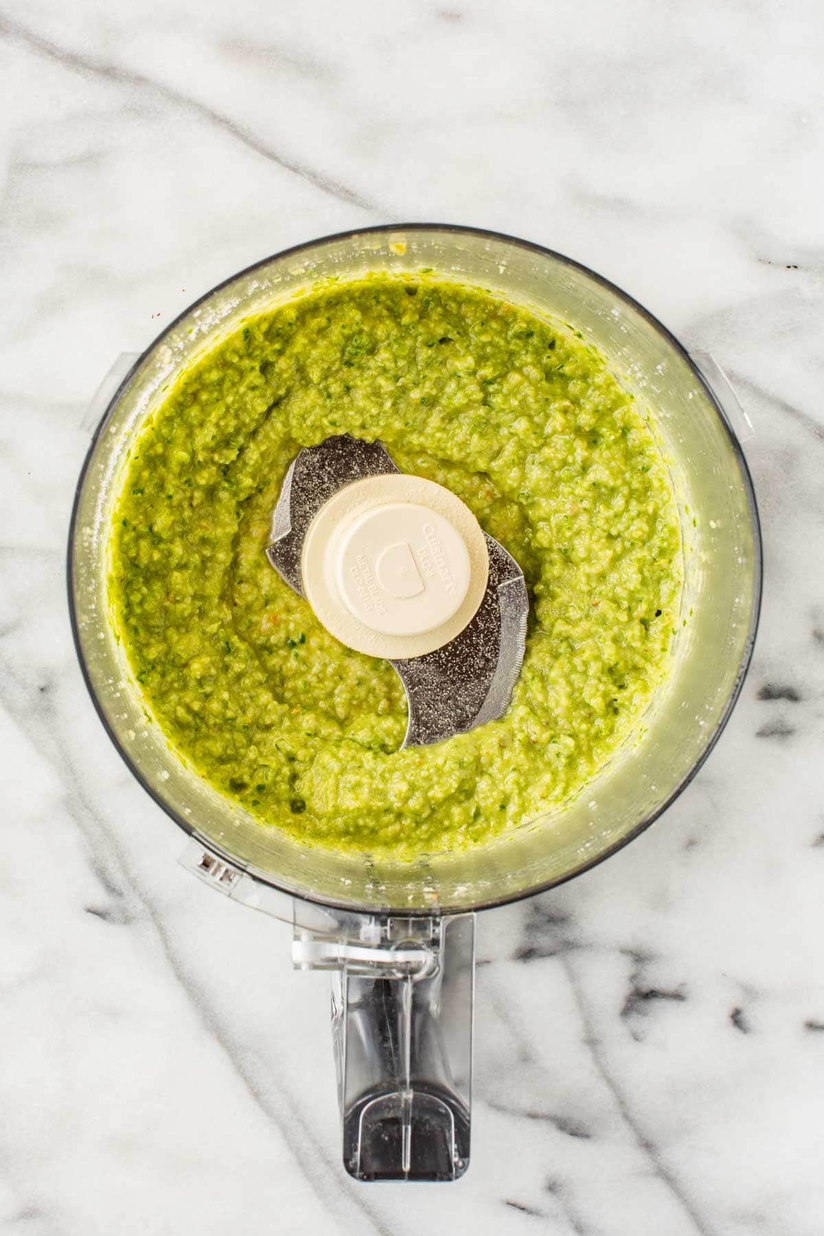 Smooth and creamy garlic scape pesto with a vibrant green hue, freshly processed and ready to serve.