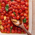 Close-up of tomato confit being scooped with a wooden spoon.
