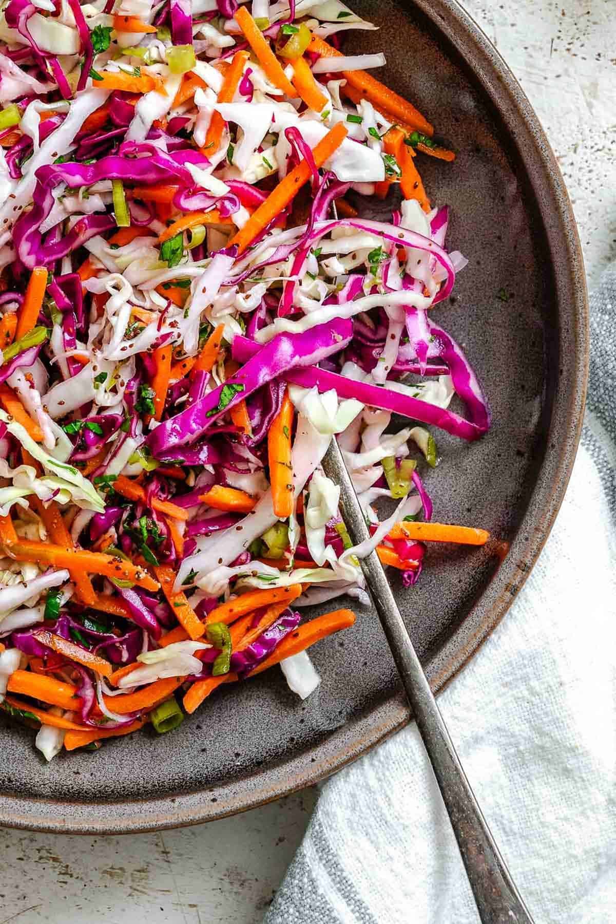 A close-up of red cabbage, green cabbage, carrots, and green onions mixed together, highlighting the texture and freshness of the slaw.