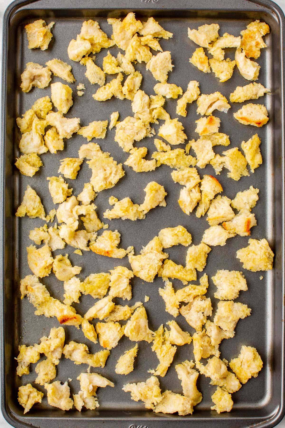 Coated bread chunks arranged on a baking sheet, ready for the oven.