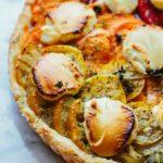 Close-up of the baked tomato goat cheese tart highlighting the caramelized edges of creamy goat cheese and the layered roasted heirloom tomatoes.