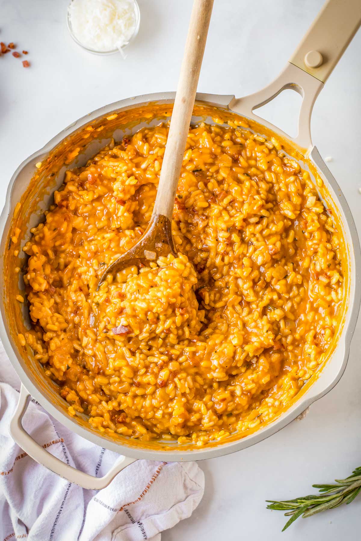 Creamy pumpkin risotto cooking in a skillet, thickening to a glossy consistency.