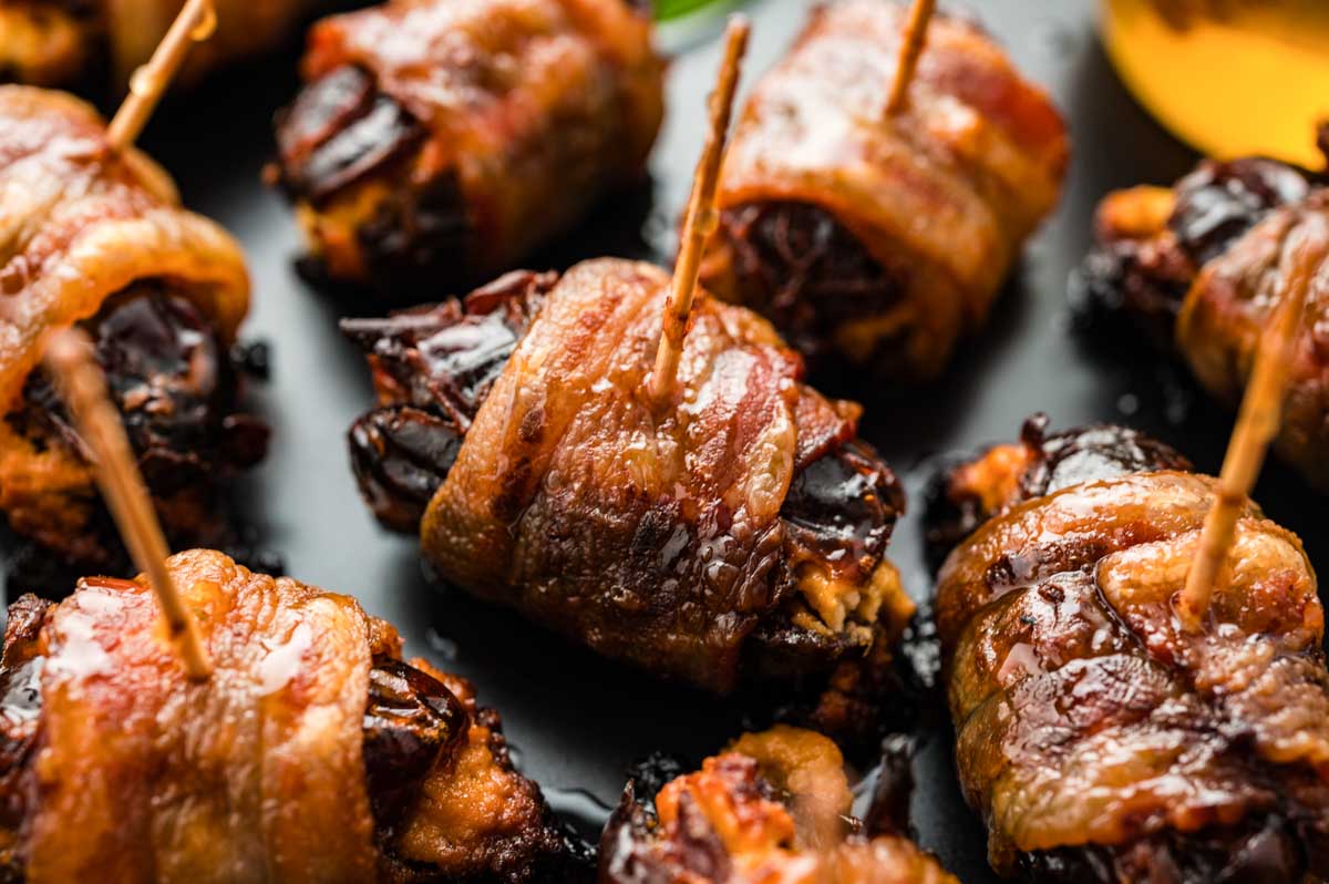 Close view of glossy bacon-wrapped dates glistening with honey, ready to serve.
