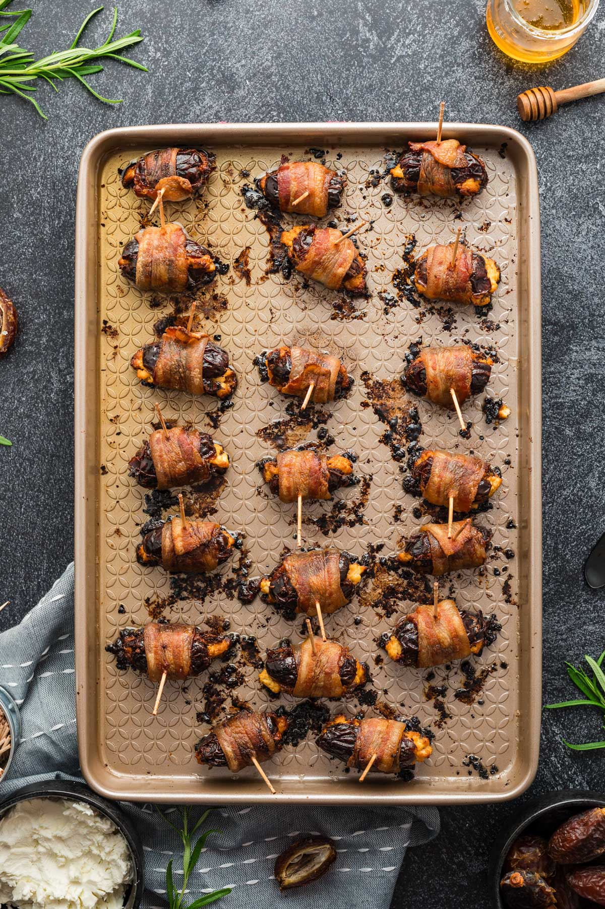 Baked bacon-wrapped stuffed dates on a sheet pan with crisp edges and melted cheese.